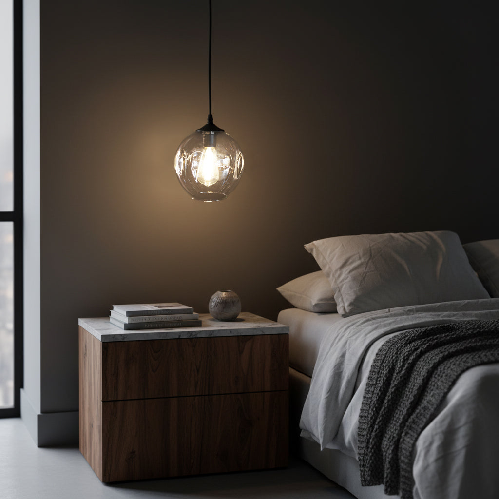 Clear glass pendant light hanging next to contemporary design bed in bedroom