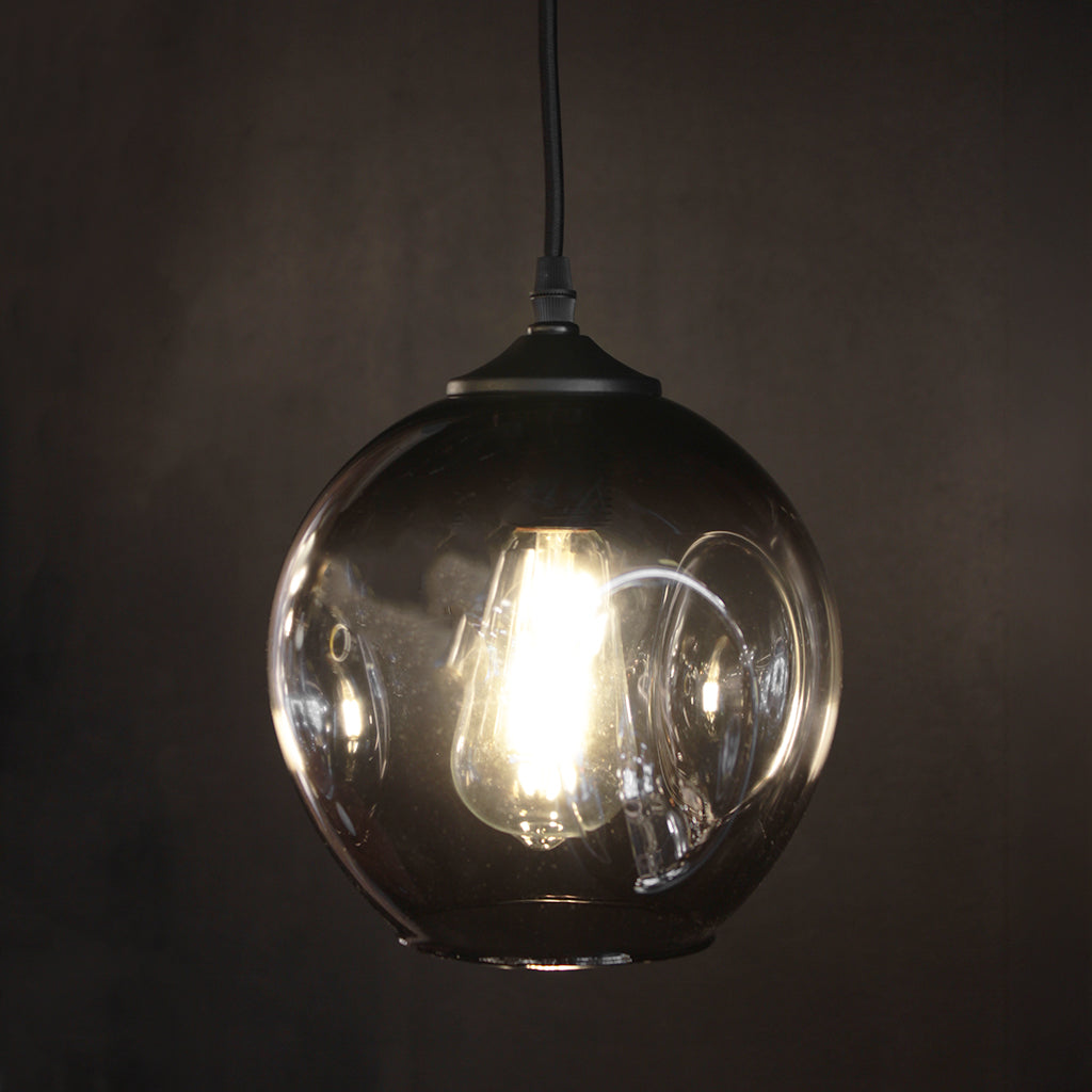 Smoke grey gradient glass pendant light with black fittings and dark background