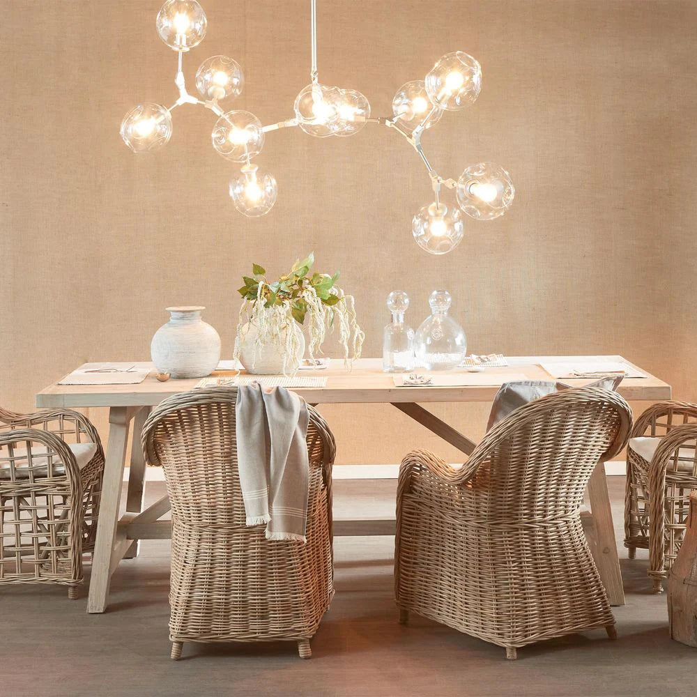 Dining room with wooden table and wicker chairs under a modern chandelier.
