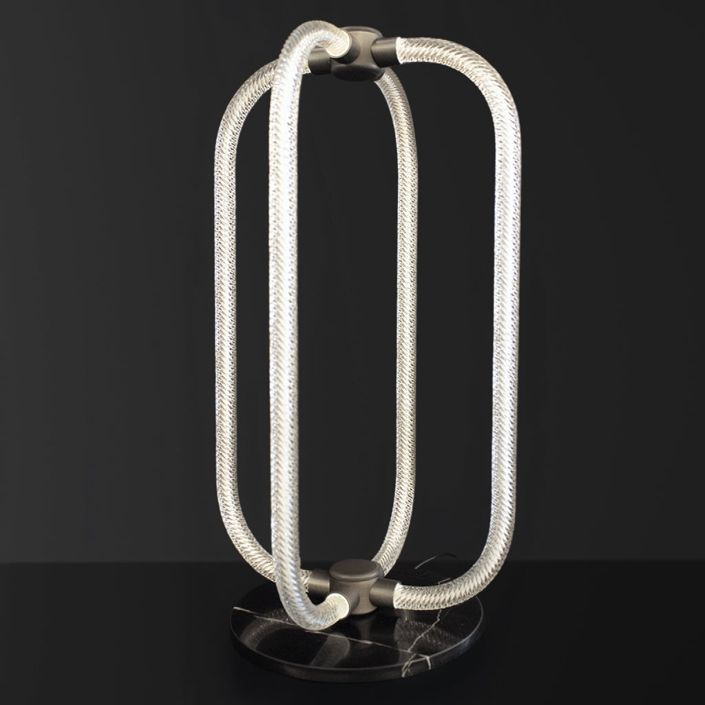 Modern table lamp with braided glass design on a black background