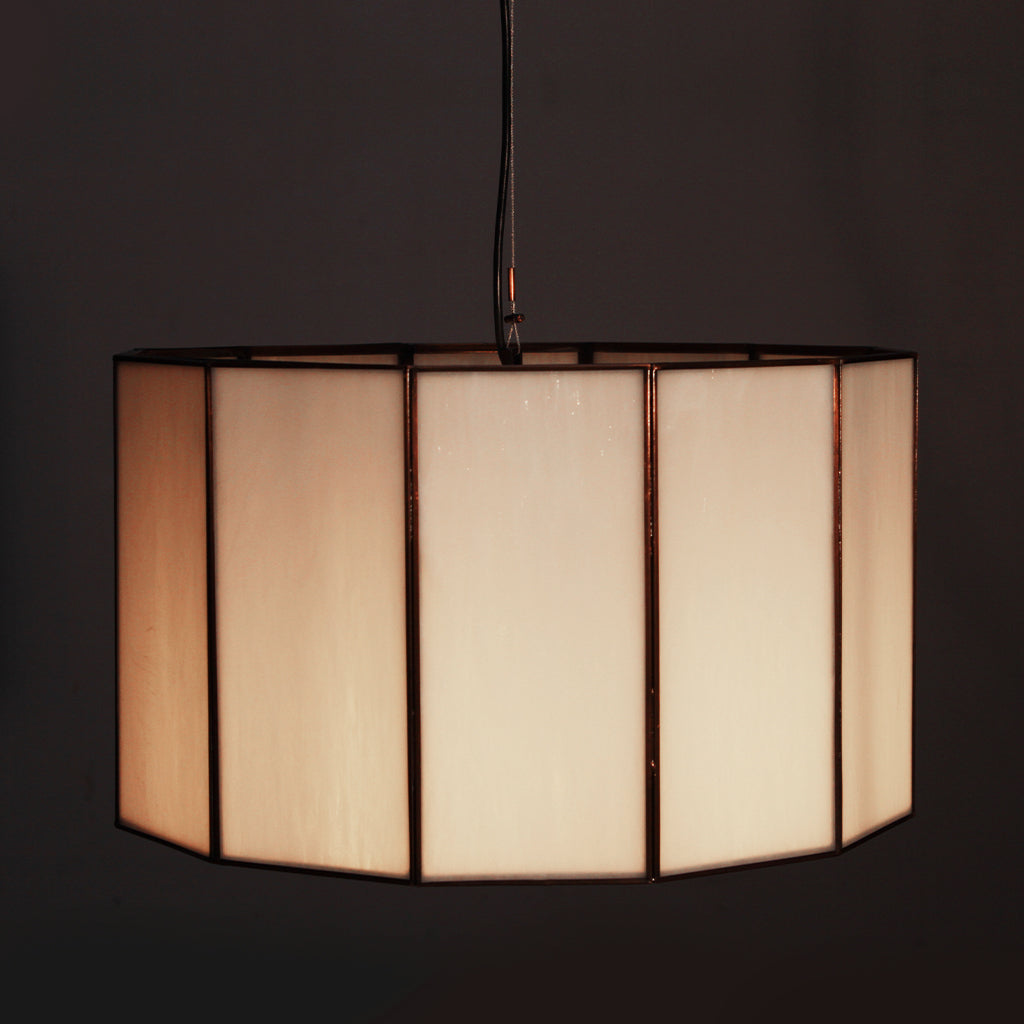 Glass and bronze pendant light with a geometric pattern on a dark background