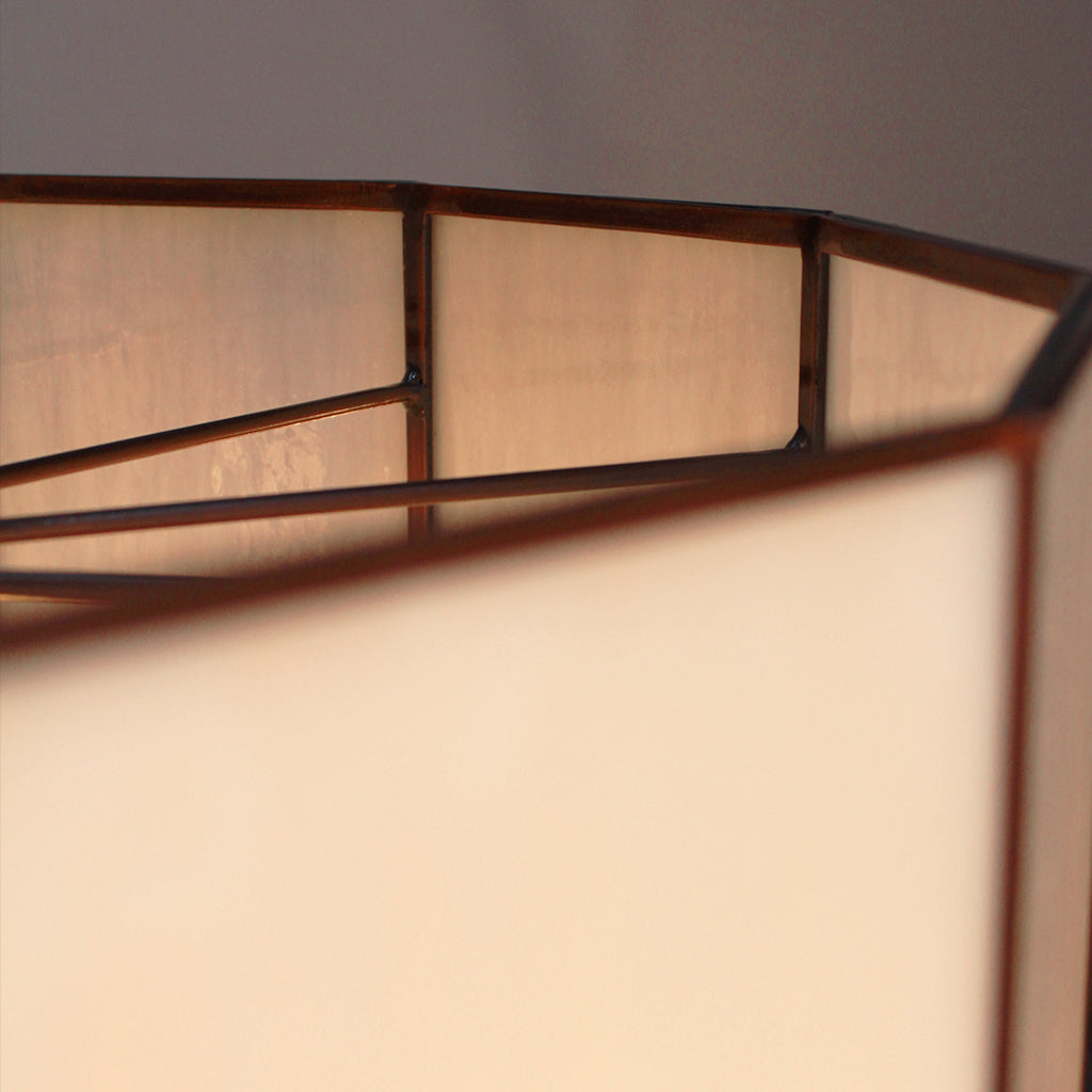 Close-up of a lamp with a white glass shade and metal frame against a neutral background