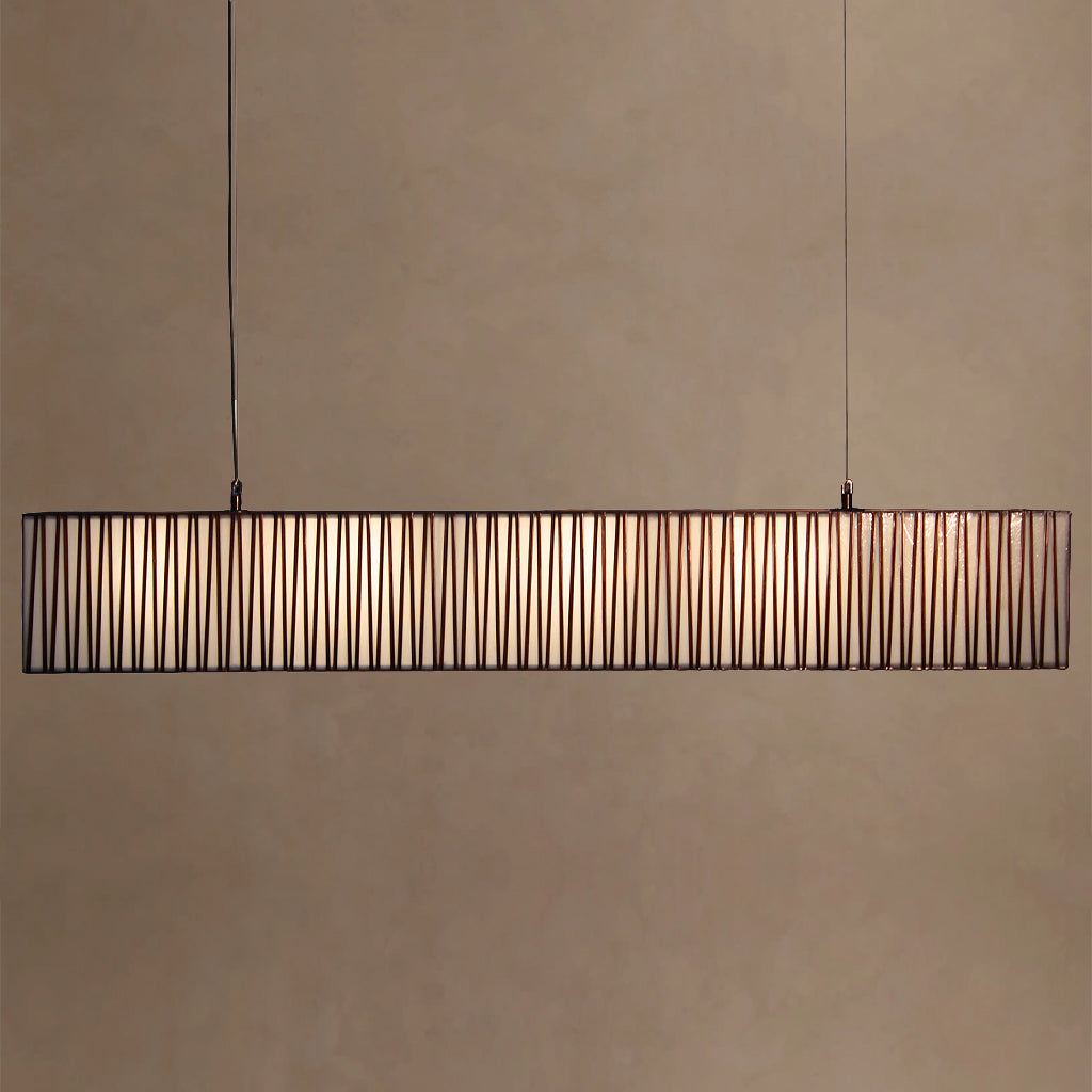 Long rectangular pendant light with a wireframe design on a beige wall.