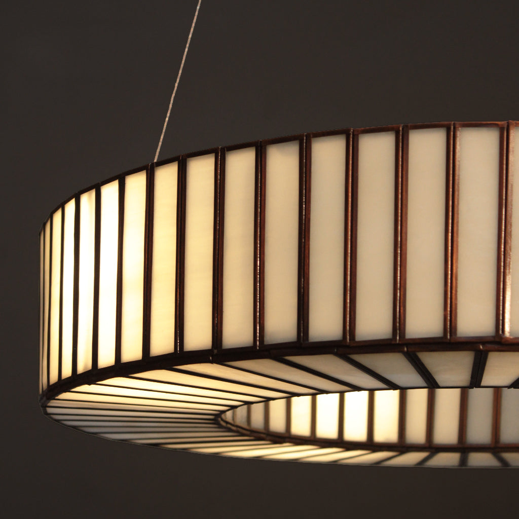 Cylindrical pendant light with a striped design on a dark background