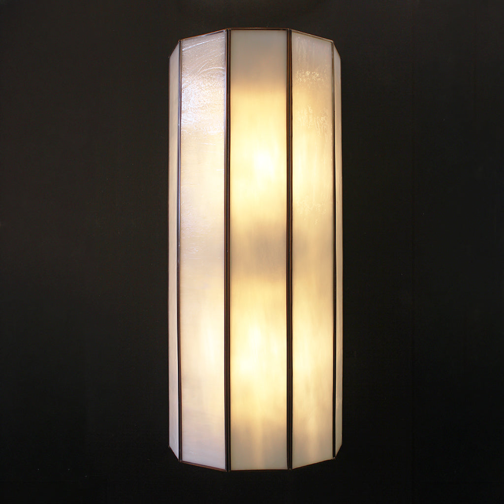 Decorative wall sconce with bronze and white glass on a black background