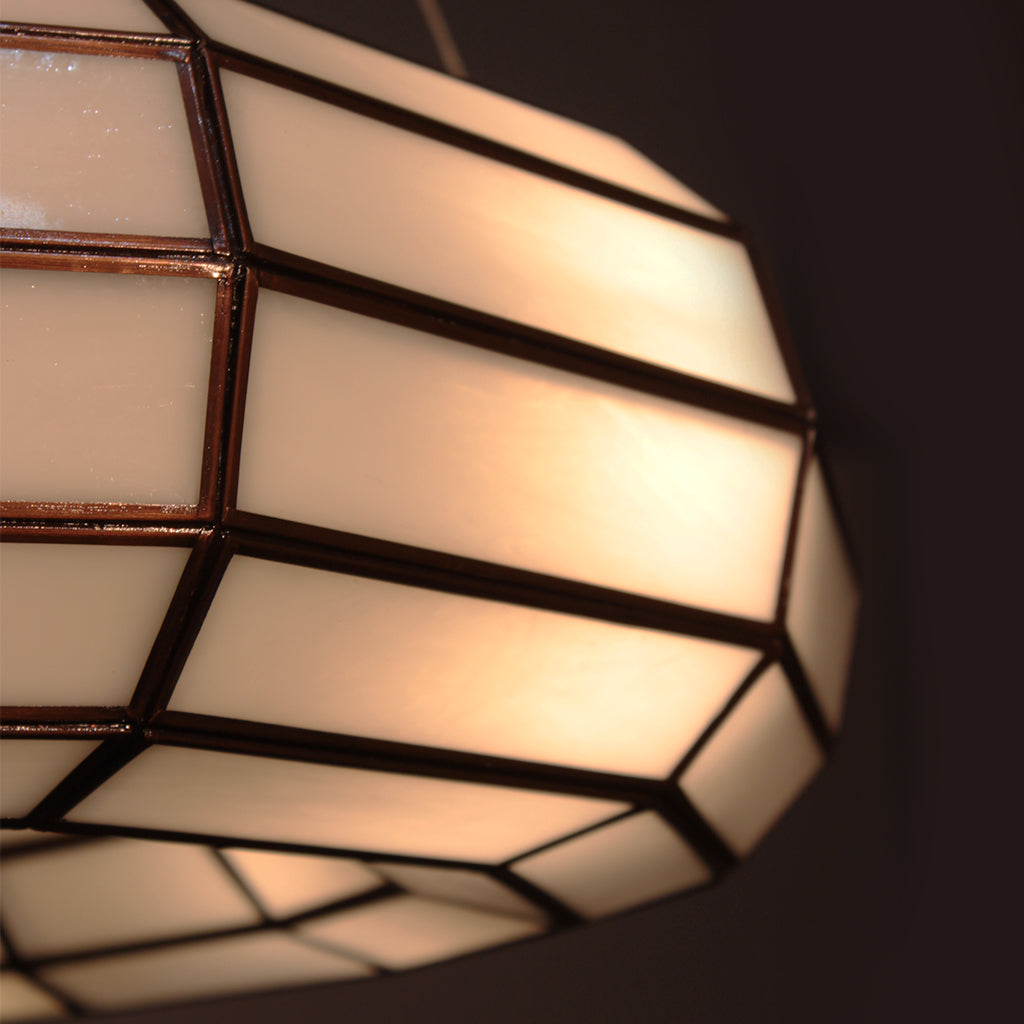 Close-up of a geometric-patterned light fixture with warm glow on a dark background