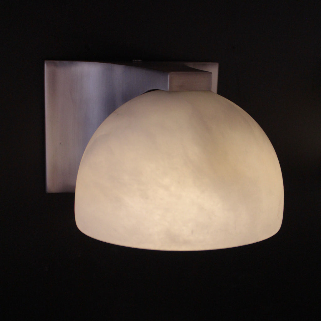 Wall-mounted light fixture with a white marble-like shade on a black background