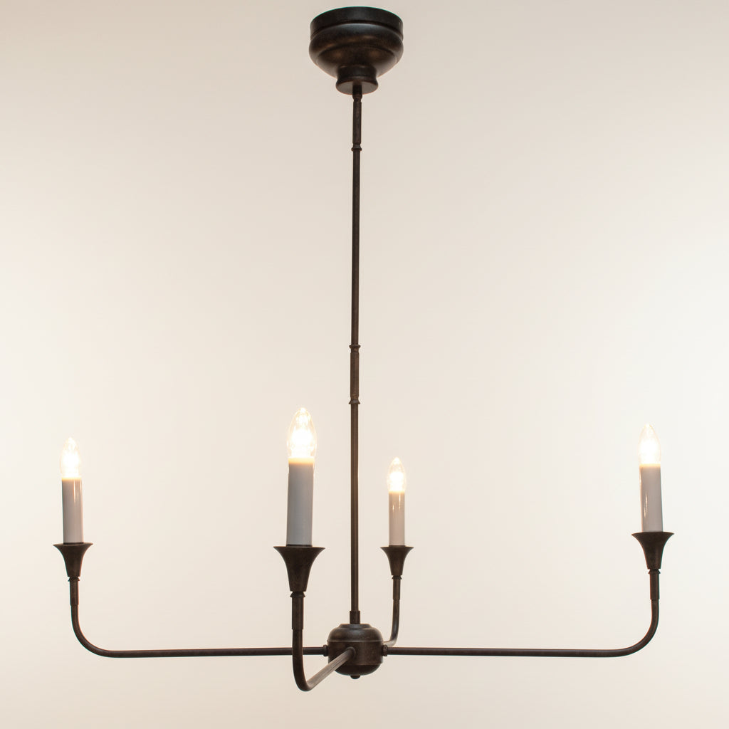 Vintage-style chandelier with four lit candles on a dark background