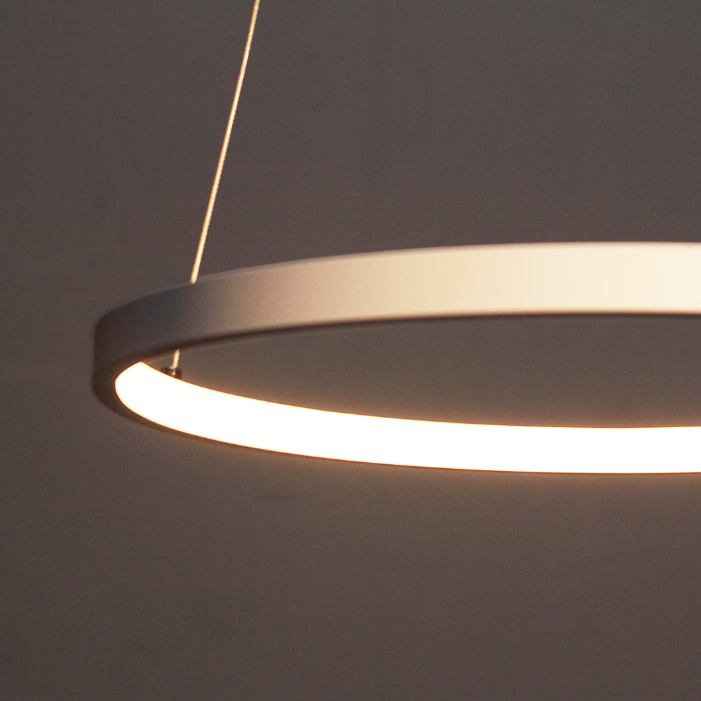 Modern pendant light with two interlocking rings on a dark background