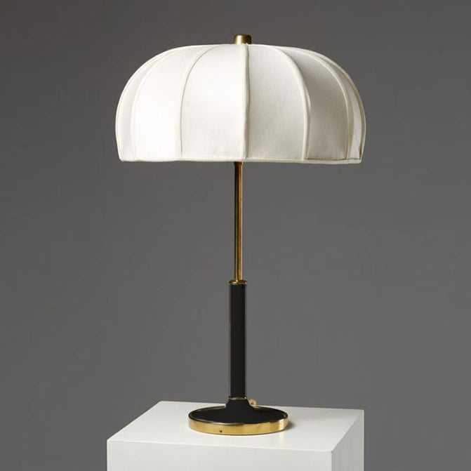 Table lamp with white shade, black base, and gold accents on a gray background