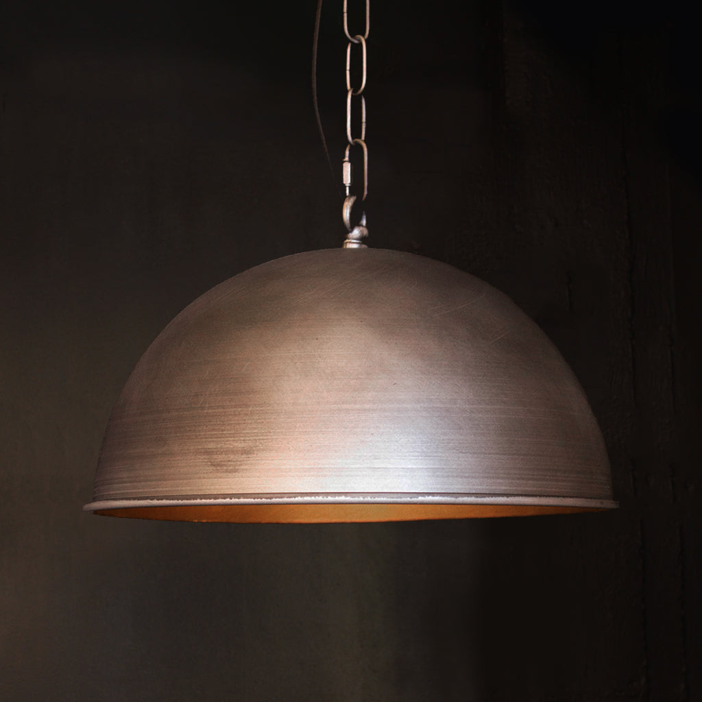 Industrial rustic silver nickel domed pendant light in front of dark background