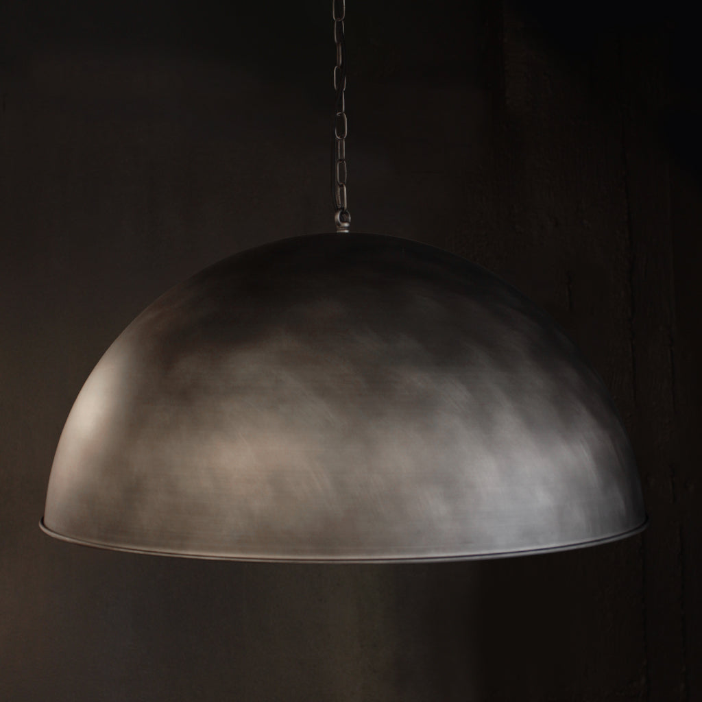 A dome-shaped pendant light with a textured, metallic nickel finish hanging from a chain against a dark background.