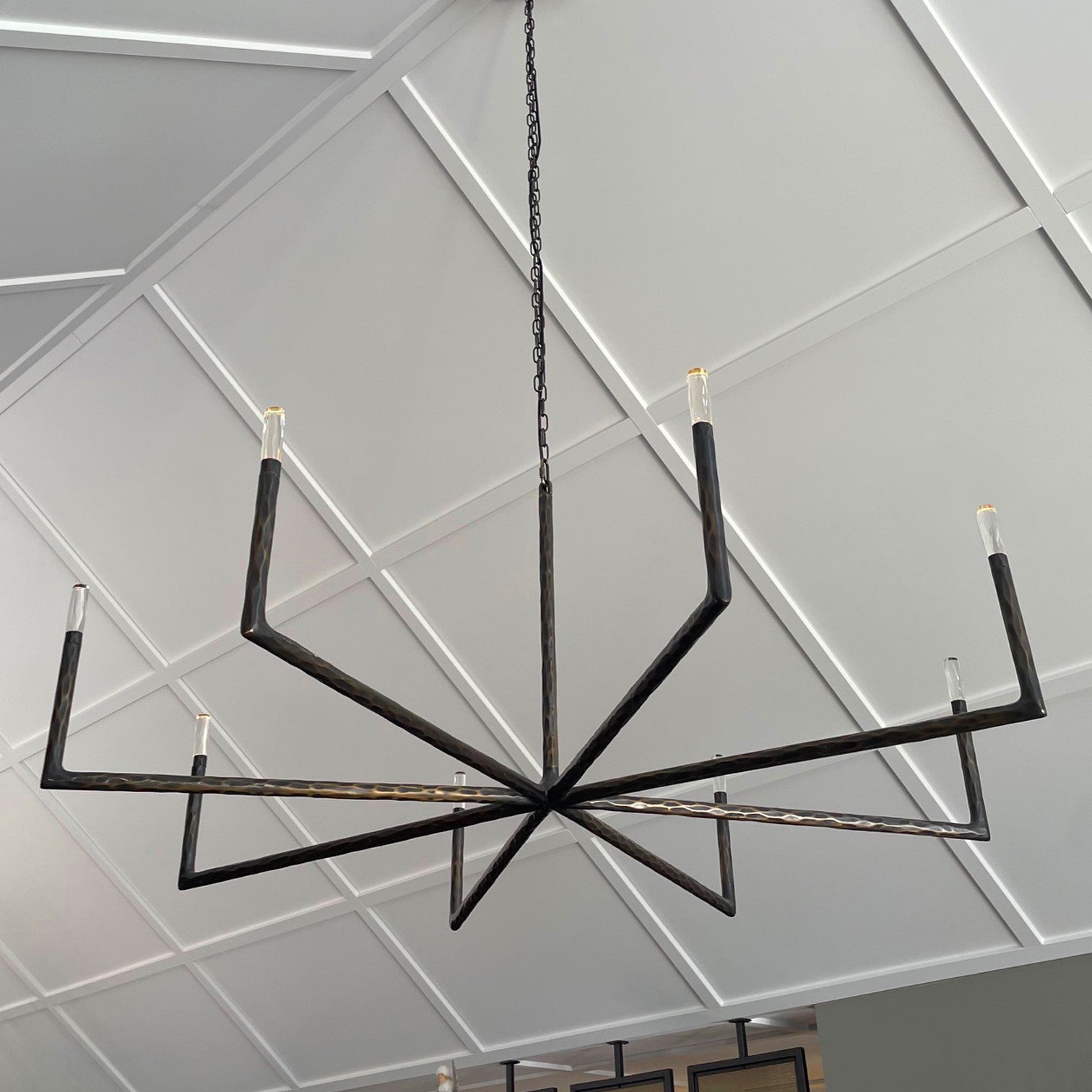 Modern chandelier hanging in a room with wooden walls and a television.
