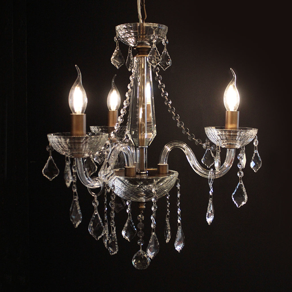 Crystal chandelier with three lit bulbs against a dark background