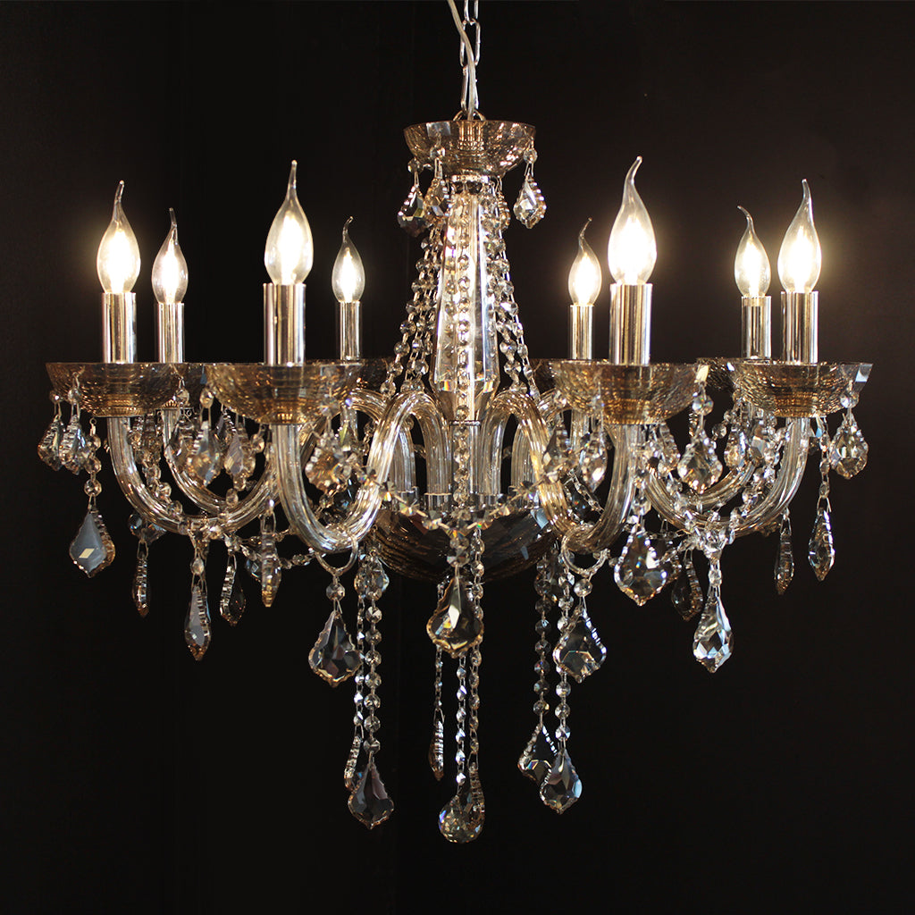 A clear crystal chandelier with faceted bowls and ribbed arms, with chrome silver accents, hanging in a room.