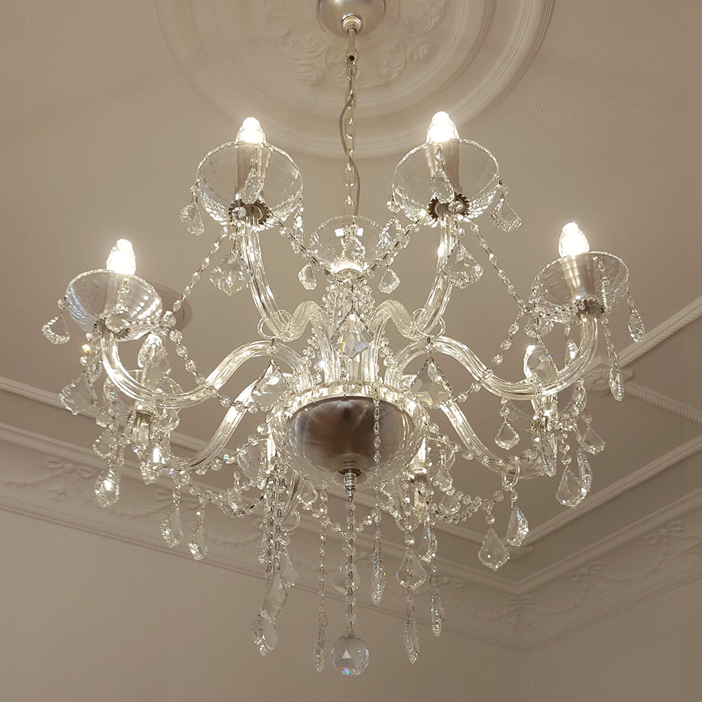 Crystal chandelier hanging from a ceiling with decorative molding.