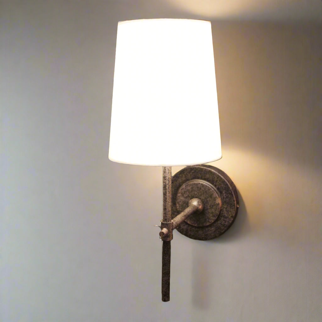 Wall-mounted lamp with white shade and metal base on a dark background