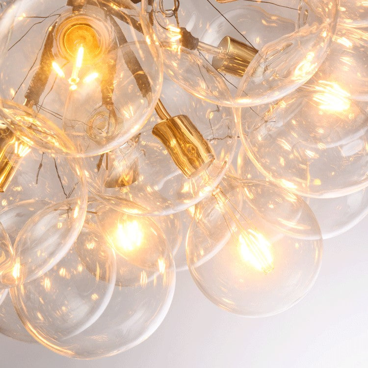 Close-up of a chandelier with clear glass bulbs and gold accents on a white background