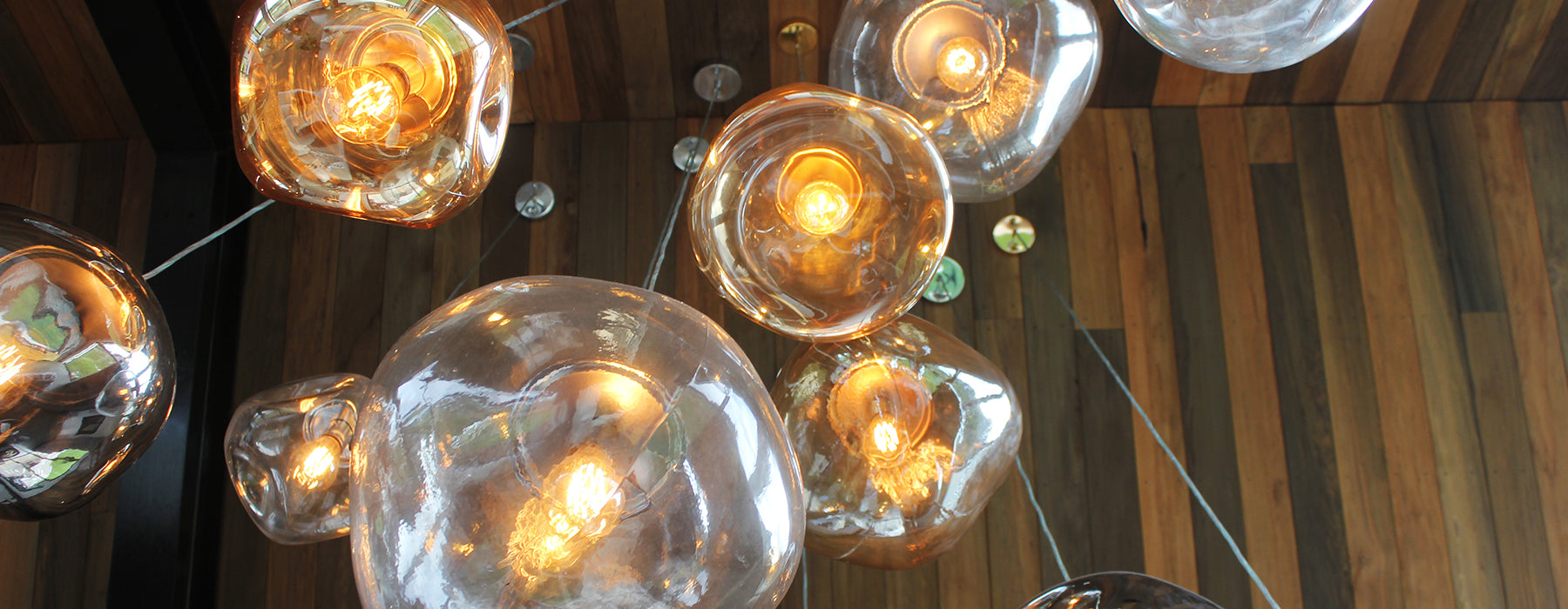 Cluster of Smelten glass pendant lights with wooden panel background, handcast Amber, Clear, Smoke Grey glass, Murano Plus