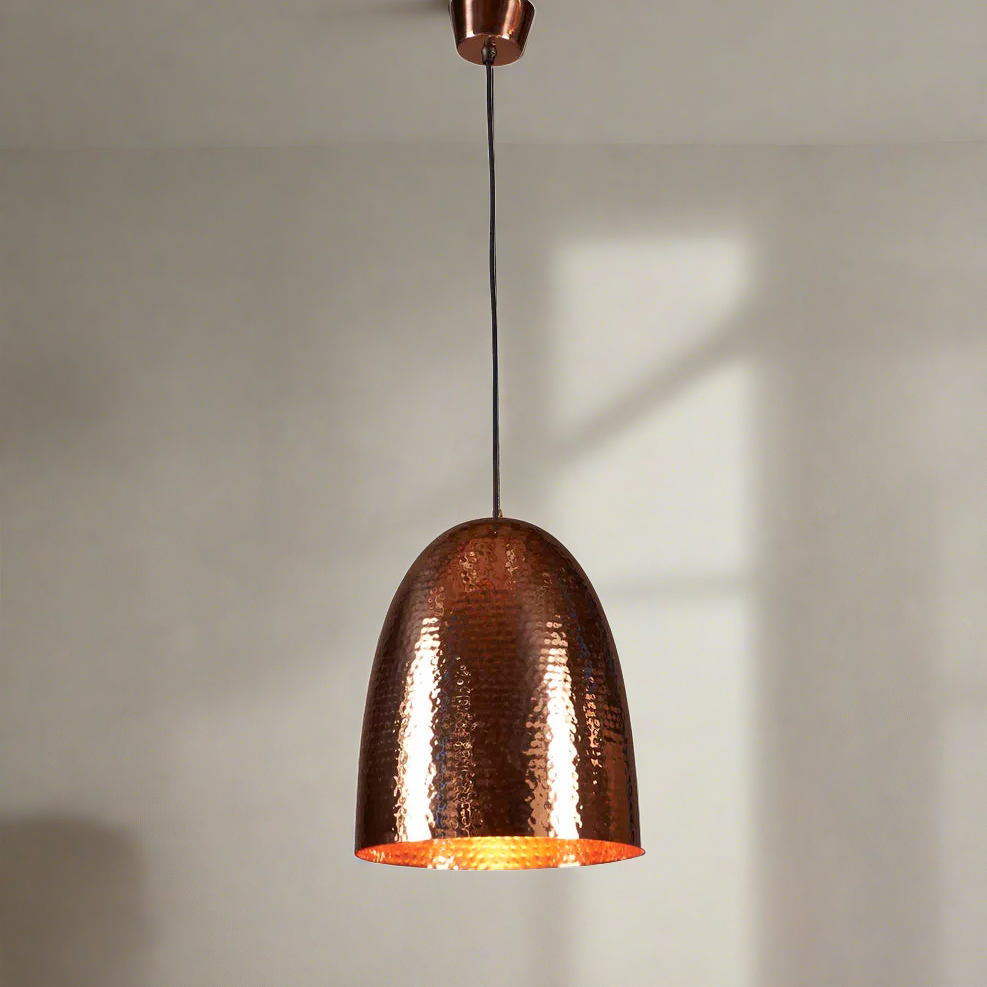 A tall domed pendant light with a hammered metal texture, constructed from a brass base, with a copper finish.