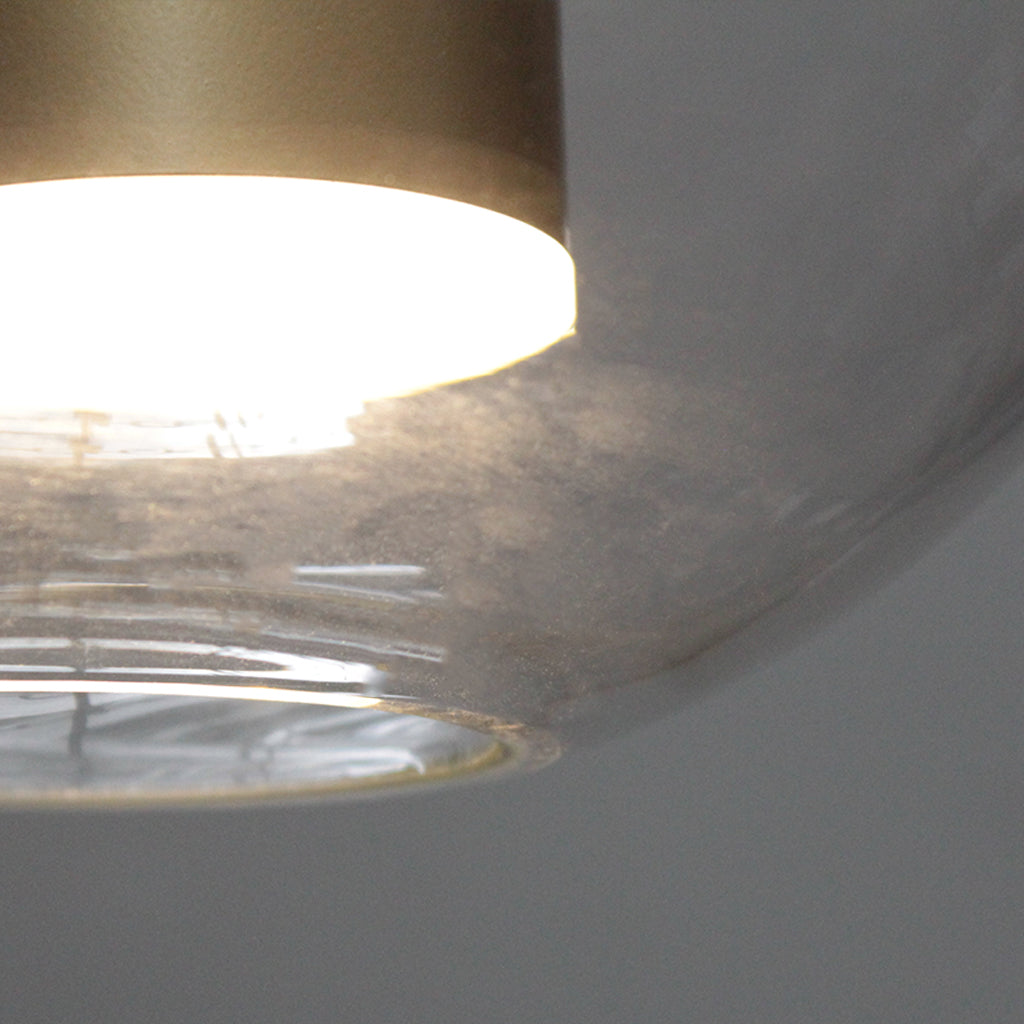 Spherical pendant light with clear glass shade and gold interior on a dark background
