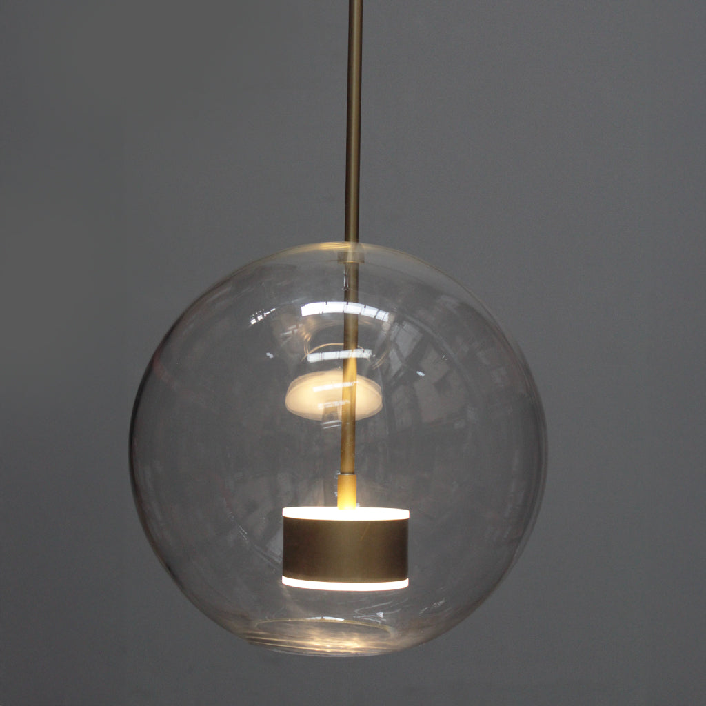 Spherical pendant light with clear glass shade and gold interior on a dark background