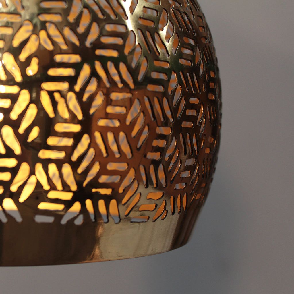 Decorative gold pendant light with geometric pattern on a plain background