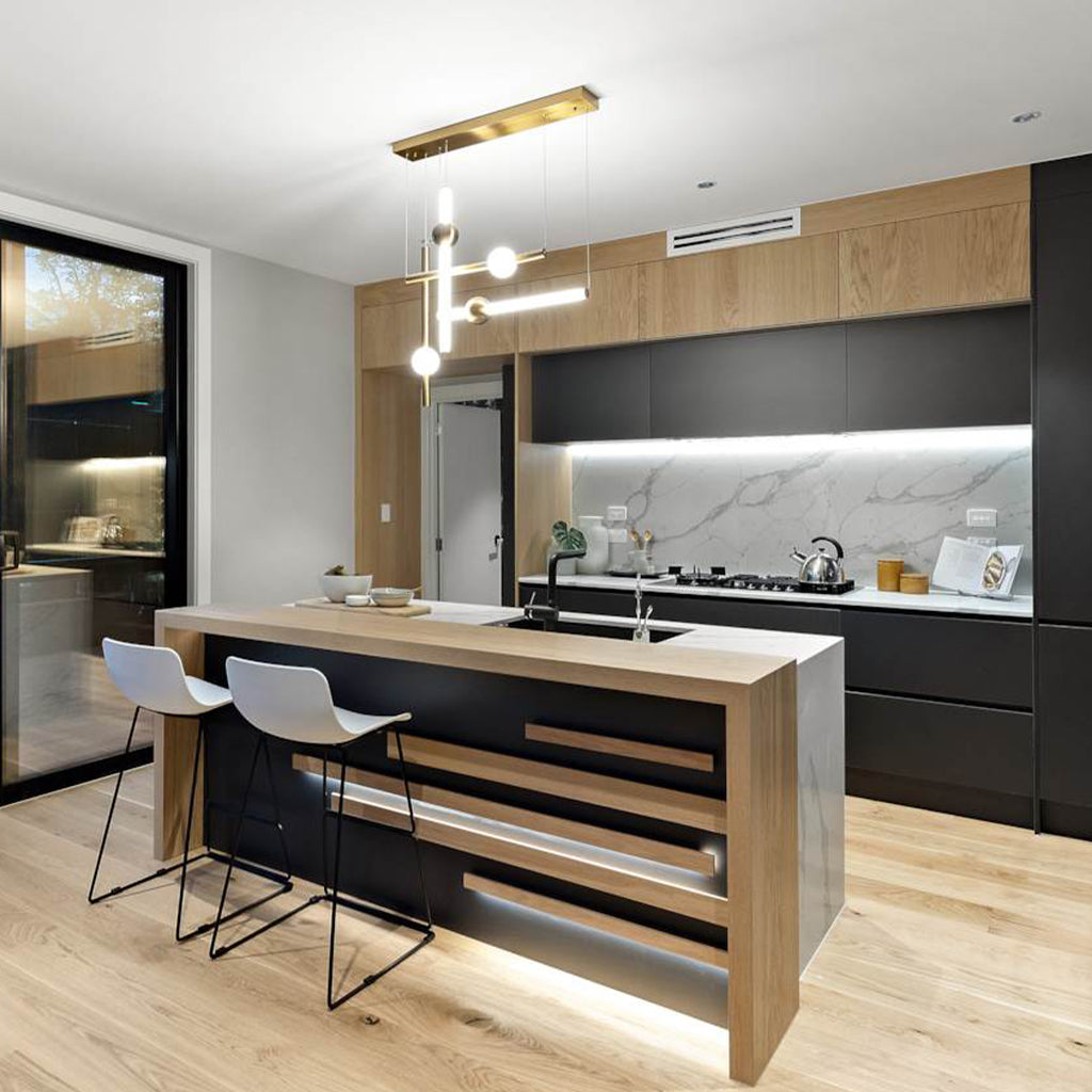 A modern kitchen island with a light oak wood top and base, black front panels, and two white bar stools, shown in a contemporary kitchen interior with wood flooring and dark cabinetry.