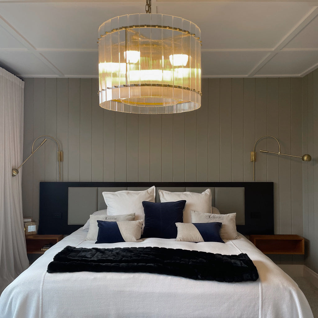 Modern bedroom with a chandelier, bed, and decorative pillows.
