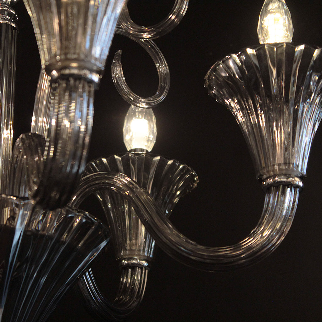 Close-up of a chandelier with smokey grey crystal and glass arms against a dark background