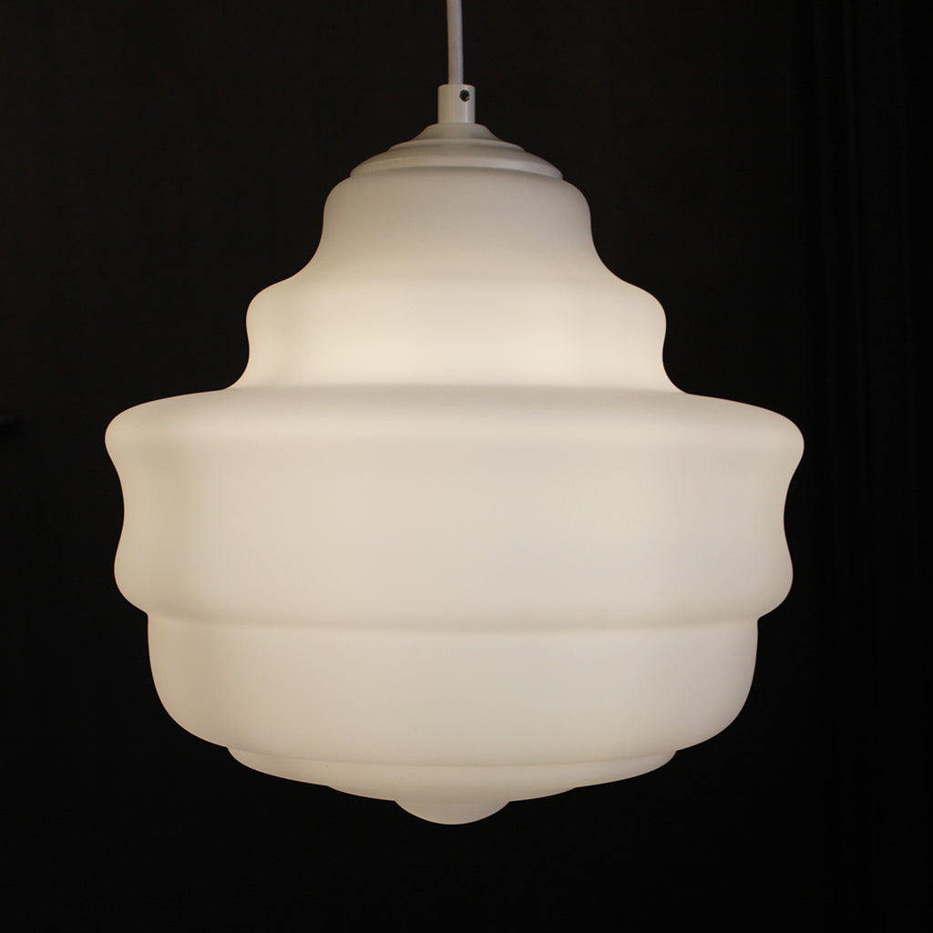 A modern, multi-tiered pendant light fixture made of frosted white glass or acrylic, glowing with a warm light against a solid black background.