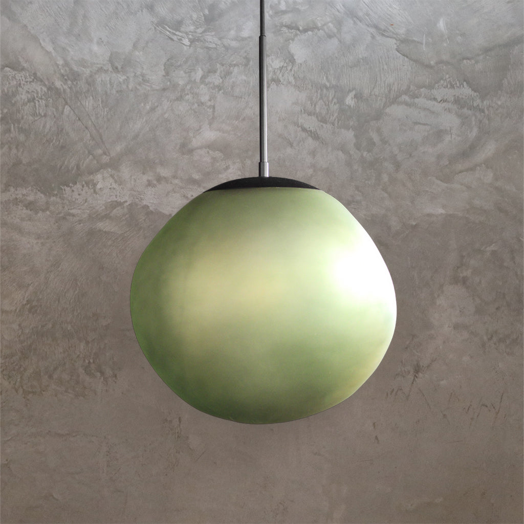 Green spherical pendant light against a textured gray wall