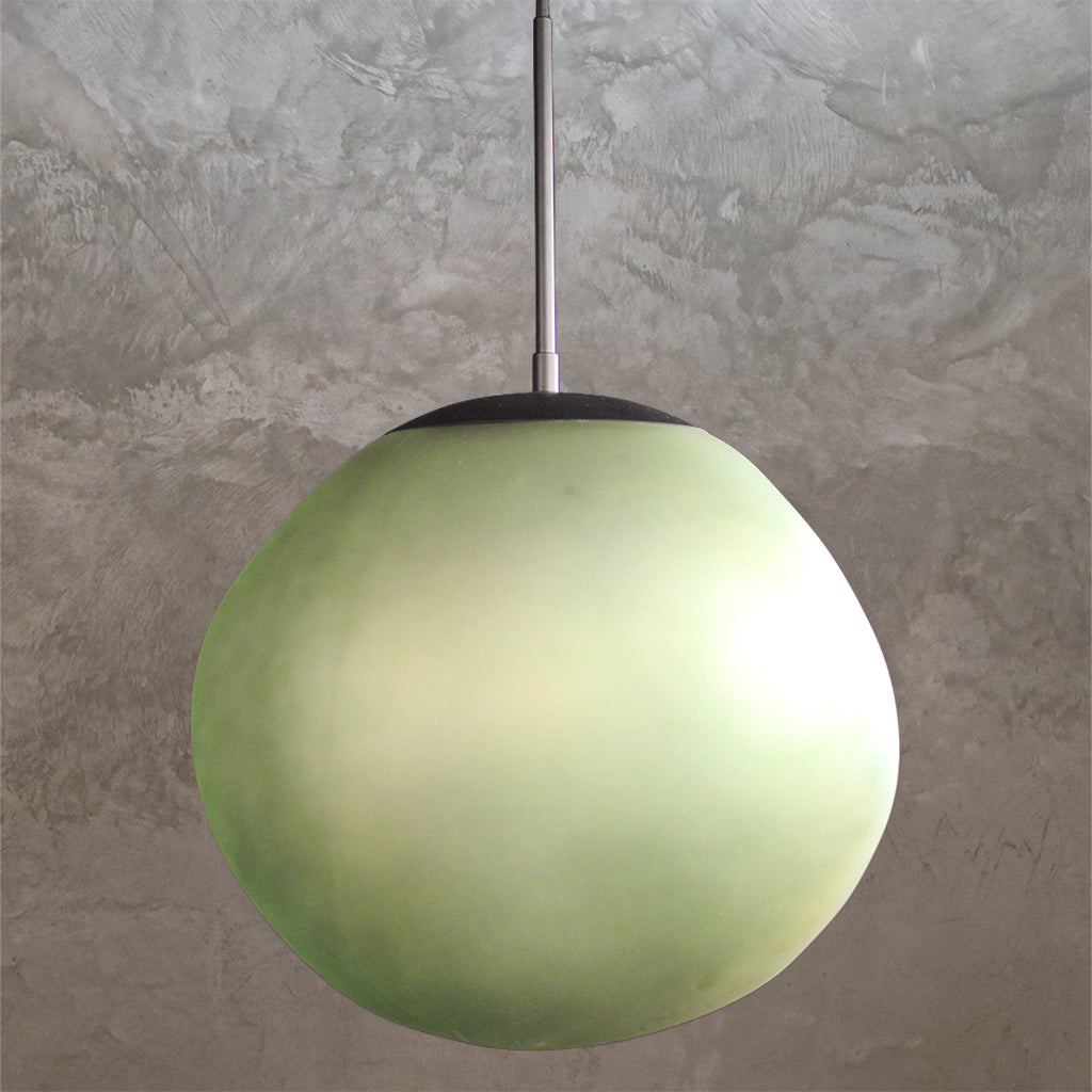 Green spherical pendant light against a textured gray wall