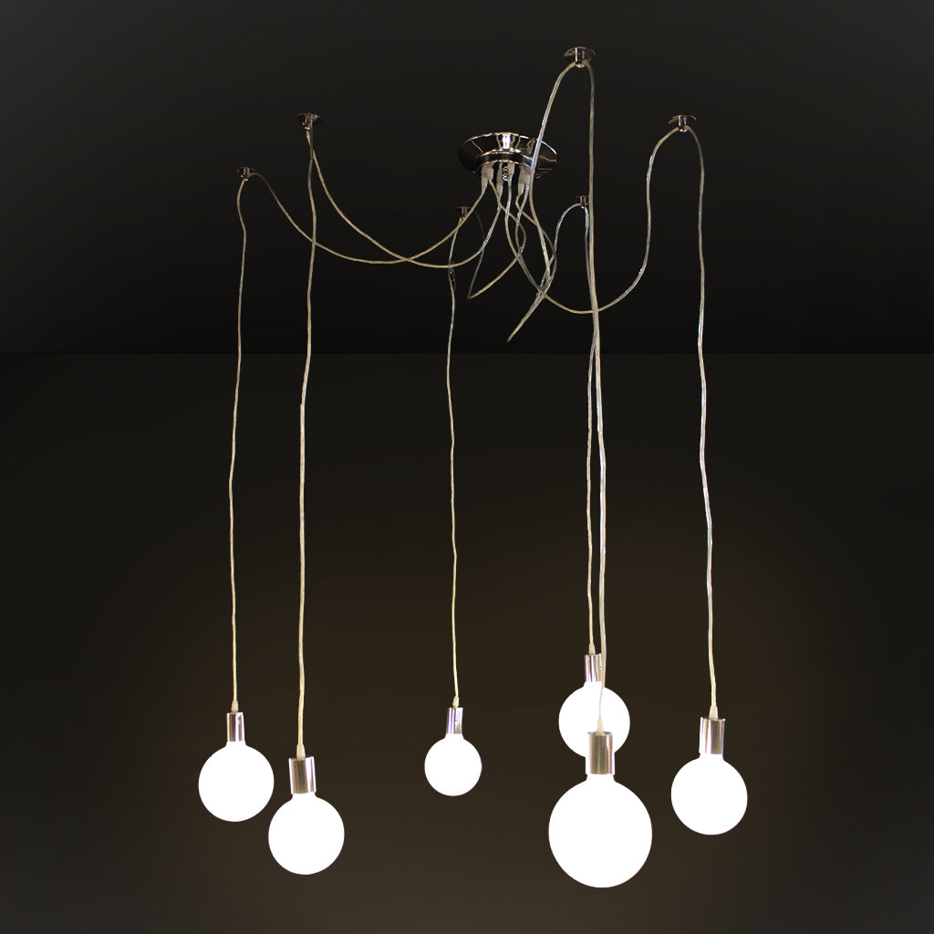 A modern multi-light pendant chandelier with six hanging Edison-style bulbs suspended from a polished metal ceiling canopy by long cords, shown against a dark studio background.