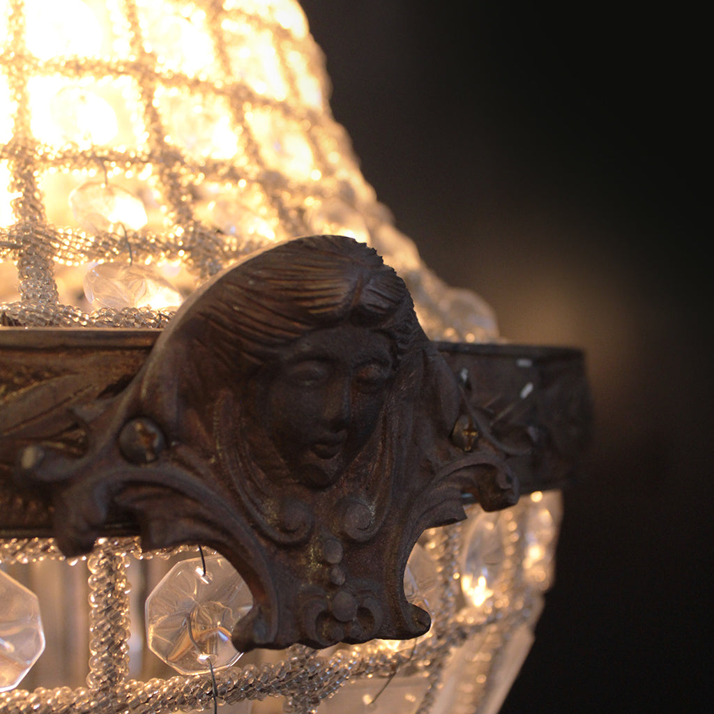 Decorative chandelier with intricate design and face detail against a dark background