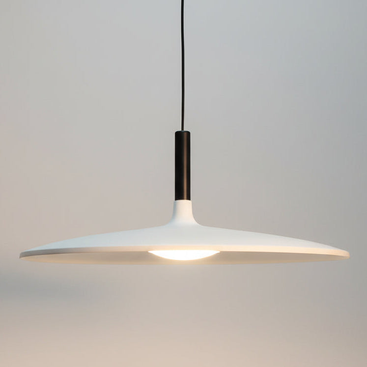 Close-up of a modern pendant light with a dark fixture and white shade against a gray background.