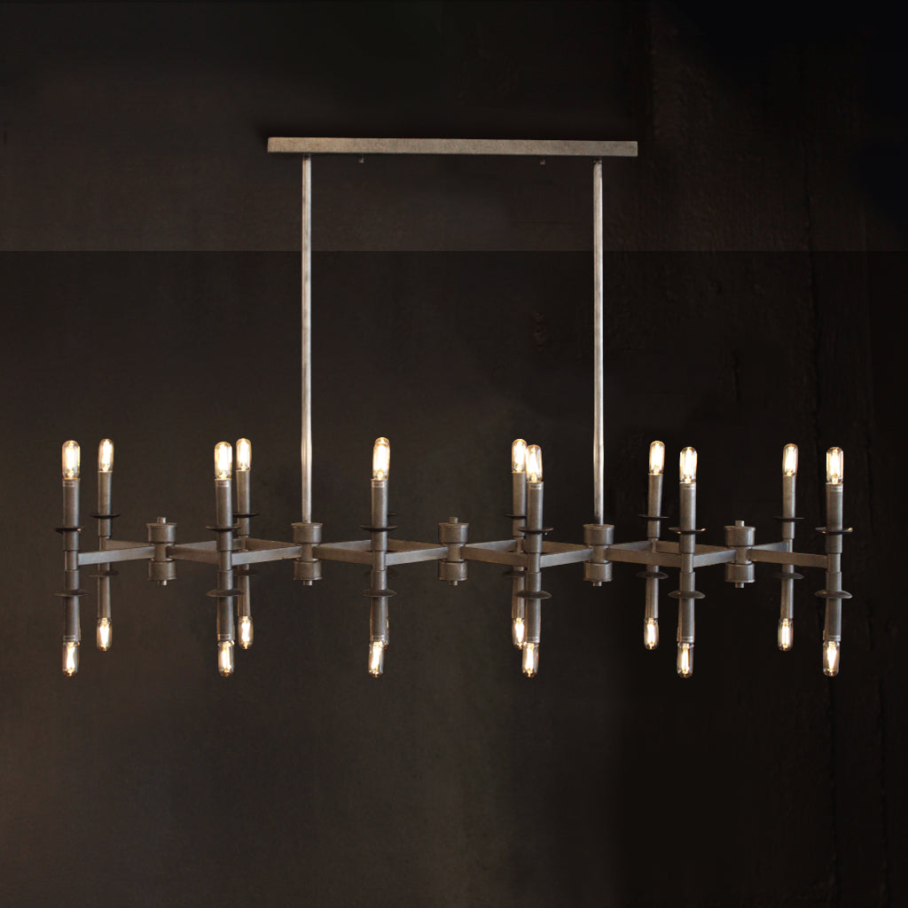 A modern industrial-style chandelier with a brushed metal frame, vertical hanging rods, and multiple candle-style bulbs, shown against a dark background with reflections below.