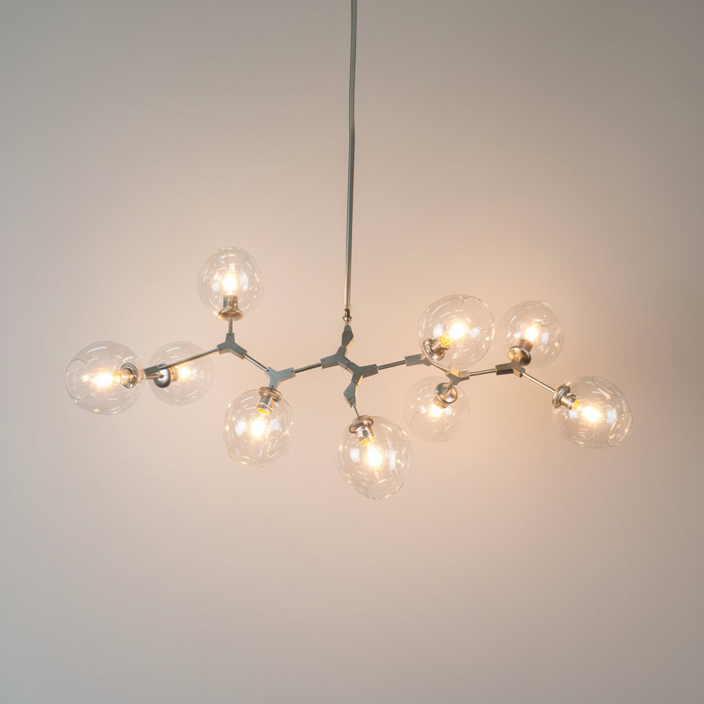 A contemporary chandelier with adjustable arms and multiple glass bulb covers, in a metallic finish.