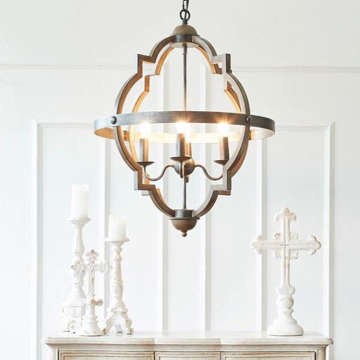 Two brass chandeliers with a geometric structure, hanging against a dark background. One chandelier is illuminated, showcasing its intricate design and multiple light bulbs.